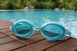 © Iryna - Blue swim goggles resting on wooden pool deck
