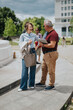 © qunica.com - A man and a woman talk and laugh while reviewing notes on a tablet during a business meeting. The casual colleagues continue their outdoor conversation beside a city plaza, smiling and engaged.