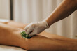 © qunica.com - Gloved esthetician pressing a wax strip onto a client's bare leg for hair removal. Professional spa treatment at a beauty center focused on smooth skin and comfort.