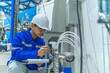 © reewungjunerr - Asian engineer working at Operating hall,Thailand people wear helmet  work,He worked with diligence and patience,she checked the valve regulator at the hydrogen tank.