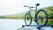 © Bonsales - Bicycle attached to a car roof rack, overlooking a serene lake and lush hills, representing an adventurous spirit and exploration of the outdoors