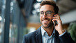 © Julia - Faceless professional man on a phone call in a glass office representing financial business looking cheerful as an executive