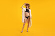 © New Africa - Beautiful woman wearing stylish swimsuit, beach kimono and hat on yellow background
