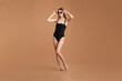 © New Africa - Beautiful woman wearing stylish swimsuit and sunglasses on brown background