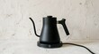 © Huzaifa - A sleek, modern, matte black electric gooseneck kettle sits illuminated on its base, ready for precise pour-over coffee or tea brewing.