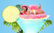 © New Africa - Beautiful woman with swim ring in glass of cocktail against pastel blue background