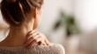 © NovaVision - Woman experiencing neck pain and discomfort, holding her shoulder with her hand