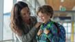 © wirachut - Mother shares smile with her son filled with back to school excitement on his first day as he wears colorful backpack and cozy shirt
