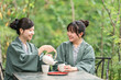 © buritora - A young Asian woman in a yukata (traditional Japanese summer kimono) drinking tea while enjoying a forest bath during her travels.