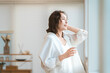 © buritora - A woman takes a shower and then rehydrates in the living room.