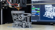 © Arifudin - A 3D printer creates a mechanical device with gears on a table in a workshop.