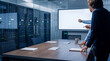 © Talia - Business professionals discuss presentation in a modern data center conference room with a blank screen.