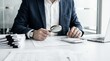 © guobao - Corporate auditor in blue suit using magnifying glass on financial paperwork, meticulous business accounting and company tax inspection.