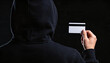 © Nattapol - Anonymous hacker committing financial fraud with stolen card, engaged cybercrime. person dark hoodie representing serious data theft and digital