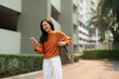 © Phimwilai - Asian woman smiling while checking smartphone outdoors
