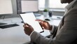 © Justlight - Medium shot of a professional using a tablet to scroll through interactive articles at a sleek office desk surrounded by softly blurred office supplies and monitors.