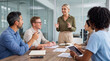 © Athena Studio - Confident business leader presenting new ideas to a diverse team in a modern office meeting room, engaging discussions.