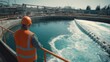 © Taiwo - Worker  wearing wearing personal protective equipment (PPE) seeing a wastewater treatment facility. Water treatment person with hard hat and safety vest inspecting water treatment basins.