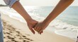 © Phlegmatic Tigress - Two people holding hands on a sandy beach with gentle waves and sunlight reflecting on the water in the background