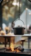 © lililia - A black pot hangs over a fire on a camping trip. The flames move around as the pot is prepared for cooking outdoors
