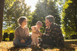 © Anna - Baby daughter and her positive parents are sitting on fallen leaves in the park in autumn on a warm sunny day. Atmospheric seasonal photo of a joyful family of three. happy parenthood