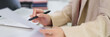 © snowing12 - businesswoman hand review financial document report data analysis office desk professional corporate workspace paper pen business meeting preparation strategy planning
