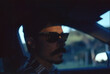 © Paz Olivares Droguett/Stocksy - Driver wearing sunglasses at sunset