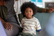 © Jovo Jovanovic/Stocksy - Child with curly hair sits next to adult on couch.