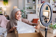 © Jovo Jovanovic/Stocksy - Woman in hijab unboxing package for online video.