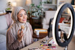 © Jovo Jovanovic/Stocksy - Woman in hijab applies makeup in front of ring light.