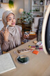 © Jovo Jovanovic/Stocksy - Woman in hijab applies makeup for a beauty vlog.