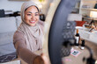 © Jovo Jovanovic/Stocksy - Smiling woman in hijab films beauty tutorial.