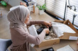 © Jovo Jovanovic/Stocksy - Woman in hijab unboxing products for online business.