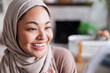 © Jovo Jovanovic/Stocksy - Smiling woman in hijab holds lip gloss applicator.