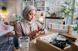 © Jovo Jovanovic/Stocksy - Woman in hijab uses phone near beauty product box.