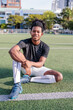 © Jovo Jovanovic/Stocksy - Smiling soccer player sits on the field