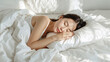 © bephoto - 白い寝具に包まれて安らかに眠る日本人女性の朝の生活写真