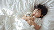 © bephoto - 犬のぬいぐるみを抱いて眠る日本人の子どもを写した生活写真