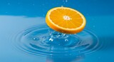 Fresh orange slice splashing into clear blue water with ripples
