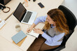 © Manu Padilla/Stocksy - Woman writing in notebook while working with laptop