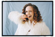 © Irina Bo/Stocksy - Woman smiles and winks while posing in white coat