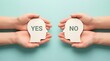 © Mary Patricia - Two hands hold paper cutouts of human heads one with YES and the other with NO inside symbolizing contrasting decisions choice thinking opinion agreement disagreement approval