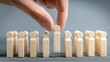 © Alfath - Human hand selects one small wooden figure from a standing line of identical figures