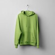 © ELVY - Light green hooded sweatshirt hangs on a metal hanger against a white wall, simple studio shot