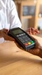 © elara - Close-up of hands exchanging a payment device over a wooden table