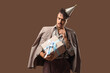 © Pixel-Shot - Thoughtful young man with Birthday gift on brown background