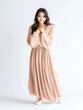 © pawczar - Full length portrait of a young asian woman in a beige dress smiling isolated on a white background