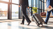 © Terry - Professional person in formal wear walking and pulling a suitcase through a bright, modern airport or office.