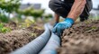 © emon - A worker carefully connects sections of drainage pipe in a garden setting.