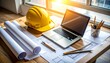 © momostudio - Architectural workspace with blueprints laptop and safety helmet.